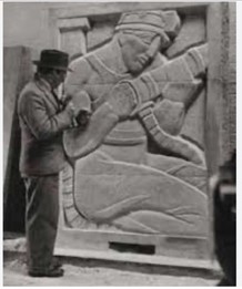 A black and white photograph of Robert Kiddey, showing his back as he looks at a bas-relief sculpture. He is wearing a suit and brimmed hat.